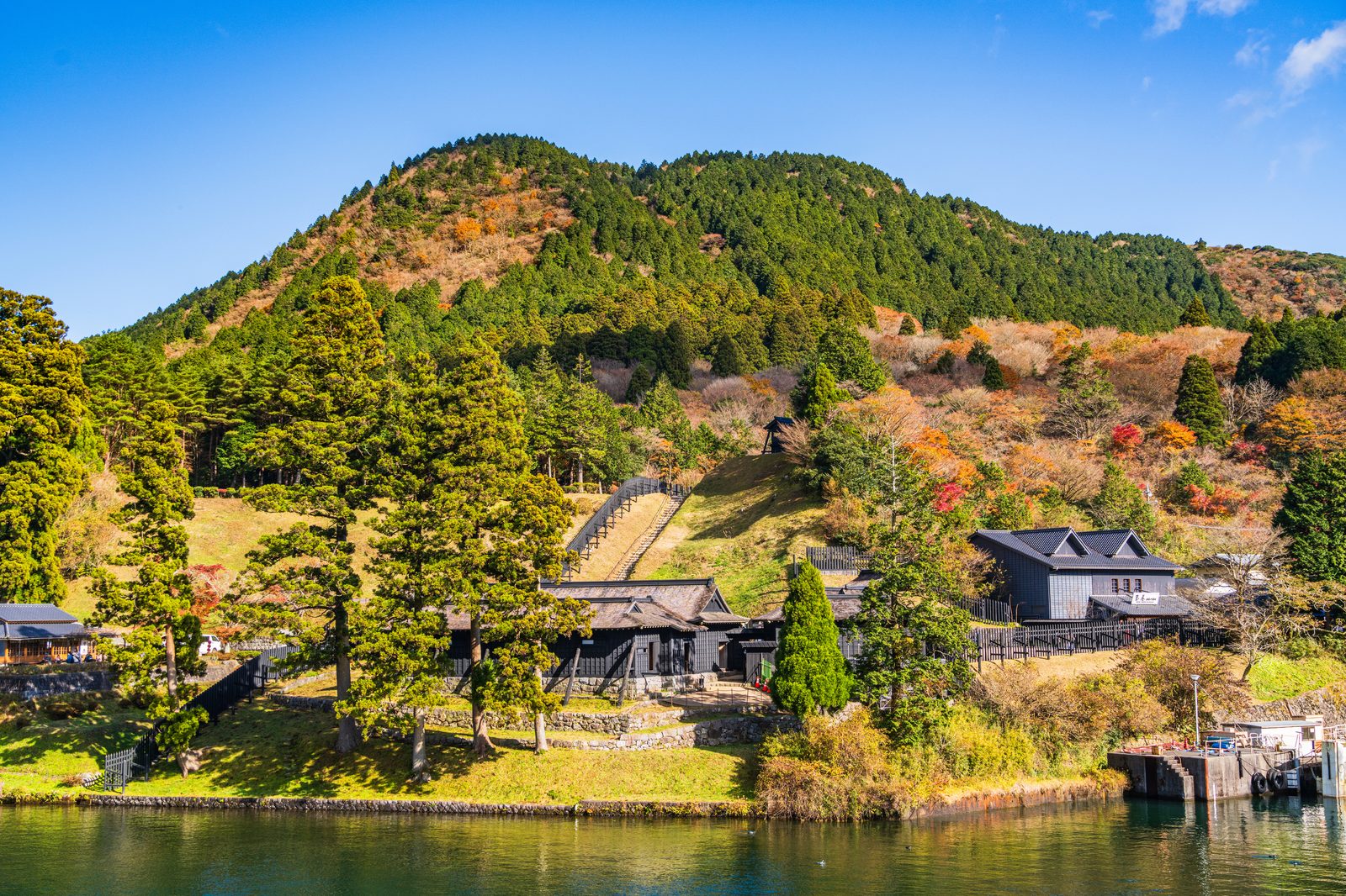 芦ノ湖の湖畔に復元された箱根関所と、色づきはじめた山肌