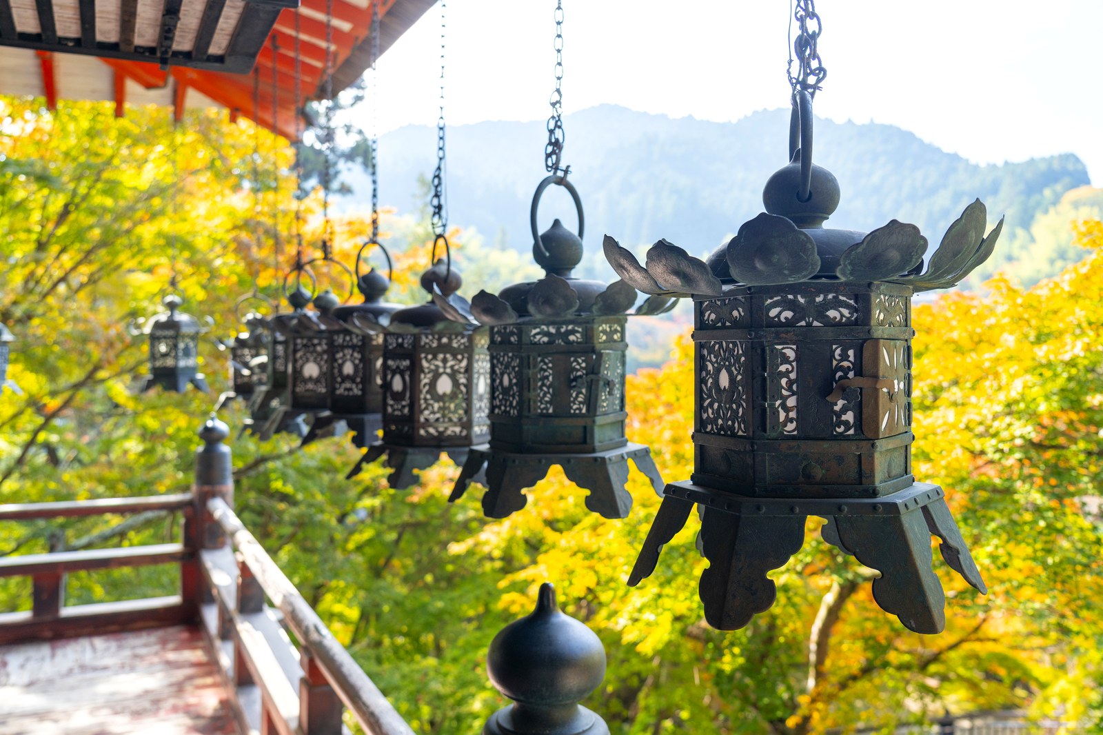 談山神社の軒下に連なる吊り燈籠と、その向こうに広がる黄葉した山並み
