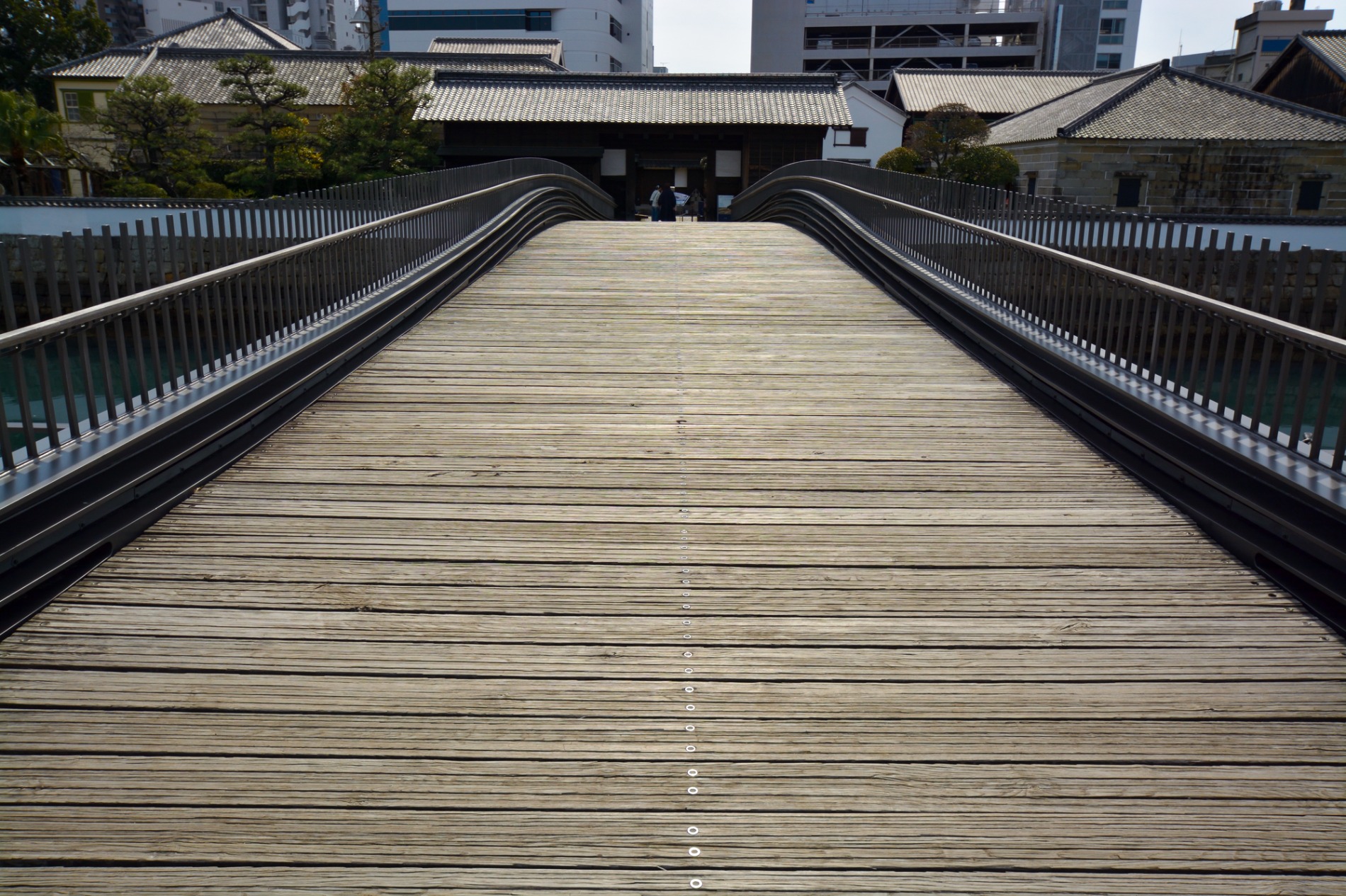 長崎市の出島表門橋。木の床板がゆるやかに反り、正面に表門が見える