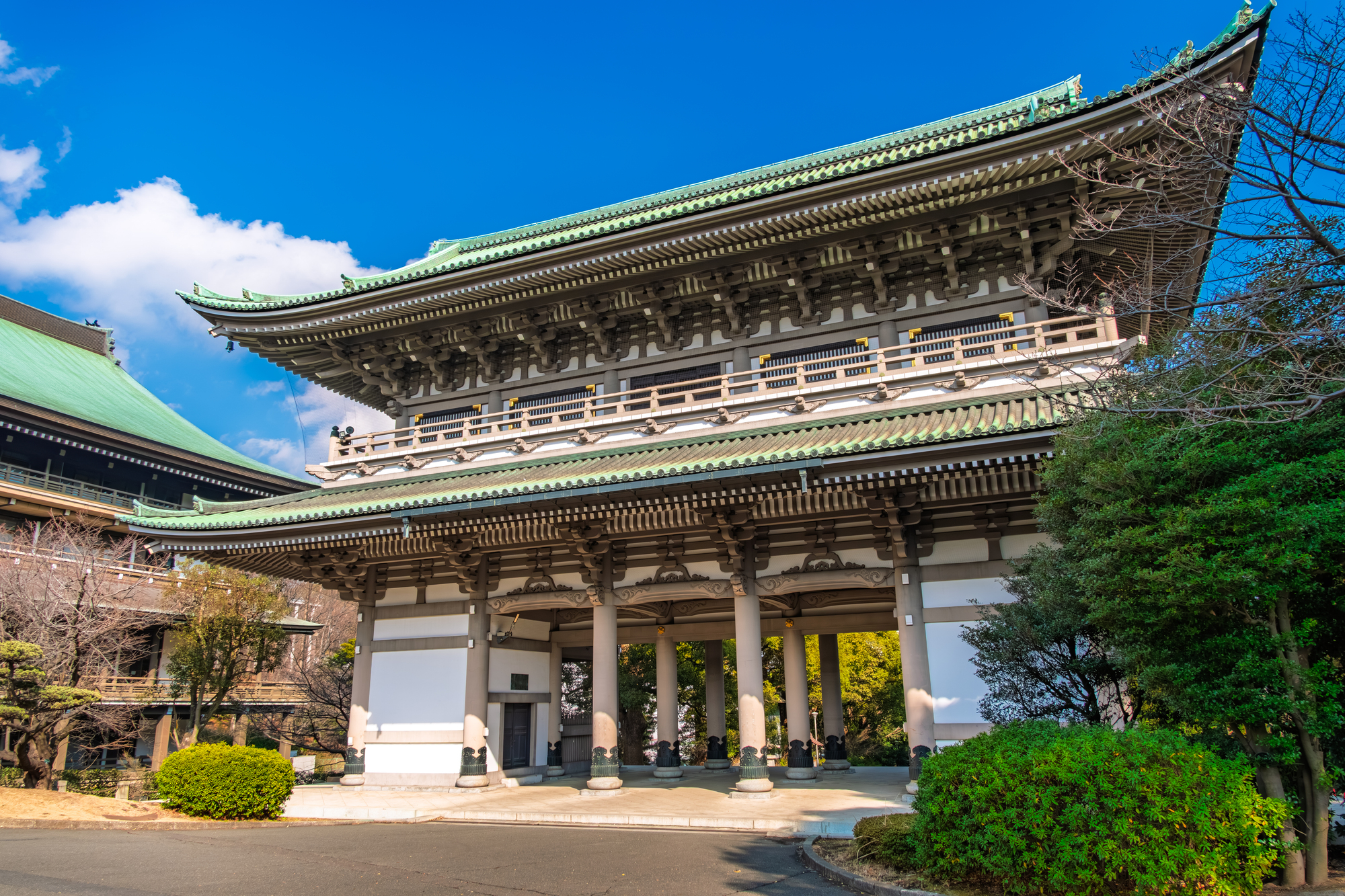 青空の下にそびえる大本山總持寺の三門。緑青色の大屋根と太い円柱が並ぶ